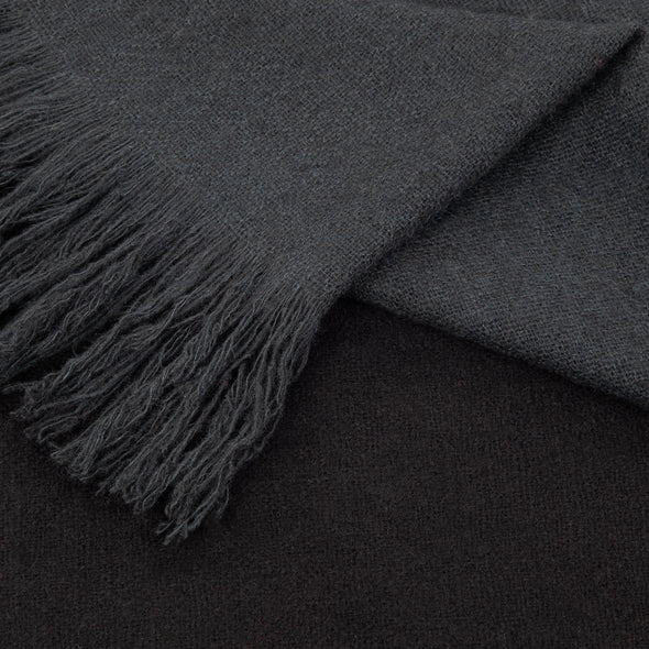 Folded detail of scarf which has been dip dyed in subtle shades of dark grey to almost black. Made from wool, yak and cashmere, a soft and luxurious scarf from Thread Tales company