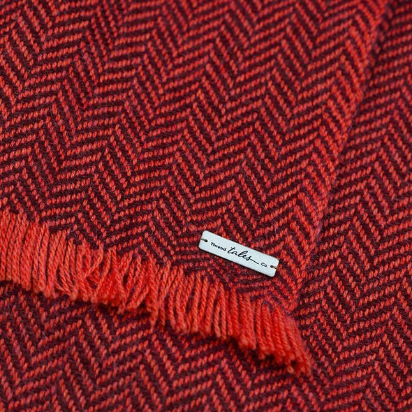 Folded detail of scarf in two tones of red herringbone weave in cashmere yak wool hand-finished with vibrant short fringe from Thread Tales company