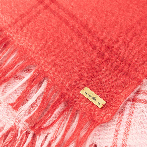 Folded detail of blush pink scarf woven with subtle open check in darker shade then dip dyed in shades of red to subtle effect. Made from wool and cashmere lightweight warm luxurious scarf from Thread Tales company 