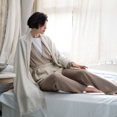 Model relaxing in Eri silk meditation wrap over caramel ombre cardigan and caramel straight leg knitted trousers