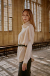 Indoor image of poncho jumper belted to give more formal look to this sleeveless poncho jumper