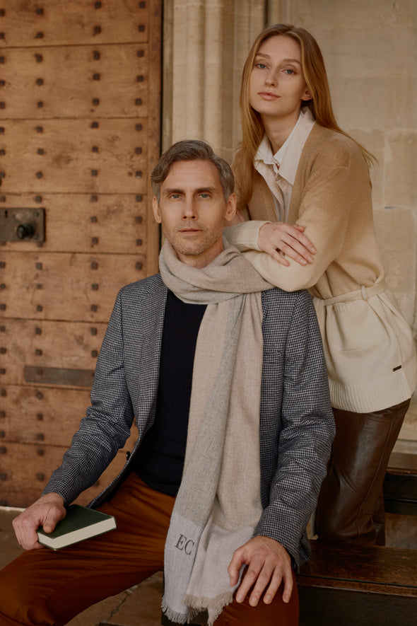 female model wearing cashmere belted caramel dip dyed cardigan and male model seated wearing two tone powder blue wrap with personalised embroidery
