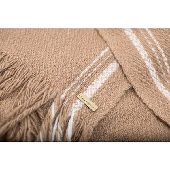 Folded detail of 100% camel wool luxurious oversized blanket wrap in camel colour with cream selvedge edge stripe. Soft and thick this cosy travel wrap is from Thread Tales company