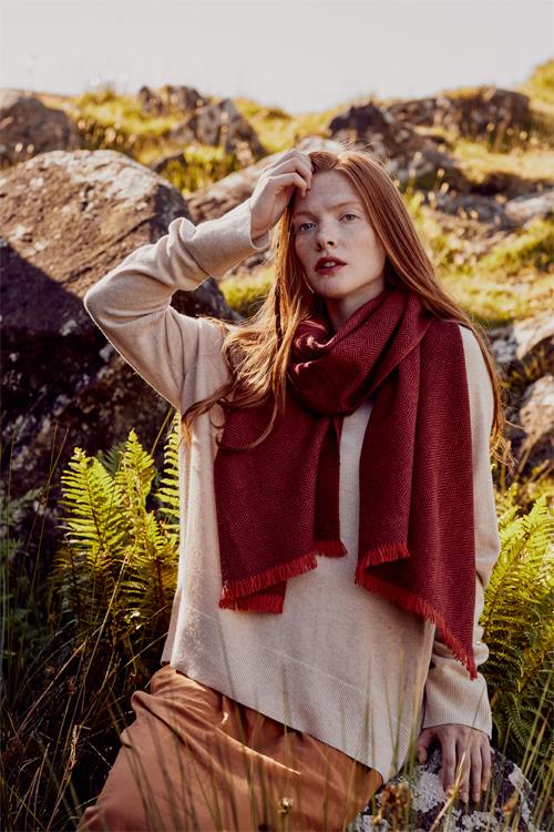 Model wearing red scarf in two tones of red herringbone weave hand-finished with vibrant short fringe from Thread Tales company