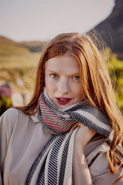 Model wearing scarf with red, black white twill stripes merino wool, handwoven heavyweight blanket from Thread Tales Company